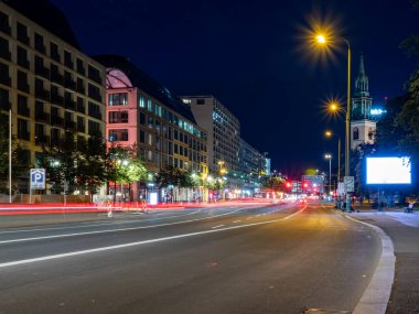 Berlin 'in gece caddelerinin manzarası ve arabaların bıraktığı ışık yolları. Gece Avrupa kenti.