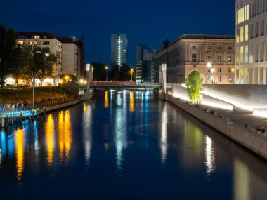 Alacakaranlıkta Berlin Nehri 'nin manzarası. Gece fenerlerinden nehir boyunca ışık izleri var..