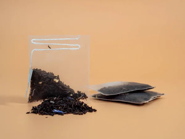 Turuncu Bir Arka Planda Şeffaf Bir Siyah Çay Poşeti Uzanıyor — Stok fotoğraf