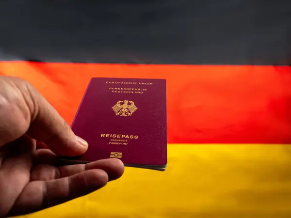 手持德国国旗背景下的德国公民护照 获得德国公民身份的概念 图库照片