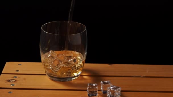 木のテーブルの上に氷が付いているウイスキーのガラス アイスクローズアップ付きウイスキー — ストック動画