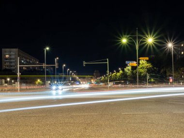 Berlin 'in gece caddelerinin manzarası ve arabaların bıraktığı ışık yolları. Gece Avrupa kenti.