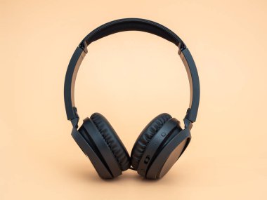 Turuncu arka planda siyah kablosuz kulaklık. Kablosuz kulaklıklar. Yakın plan..