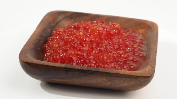 木制碗中新鲜的红色鱼子酱在白色背景上旋转 红鱼子酱特写的结构 — 图库视频影像