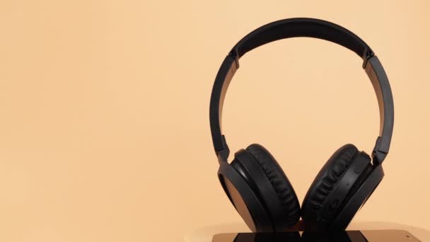 Siyah Kablosuz Kulaklıklar Turuncu Arka Planda Dönüyor Kablosuz Kulaklıklar Yakın — Stok video