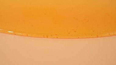 Sıvı duş jeli parlak turuncu bir arka planda zarifçe akar. Duş jelinin şeffaf dalgaları büyüleyici bir görsel senfoni yaratıyor. Sıvı duş jeli turuncu bir arka planda akar.