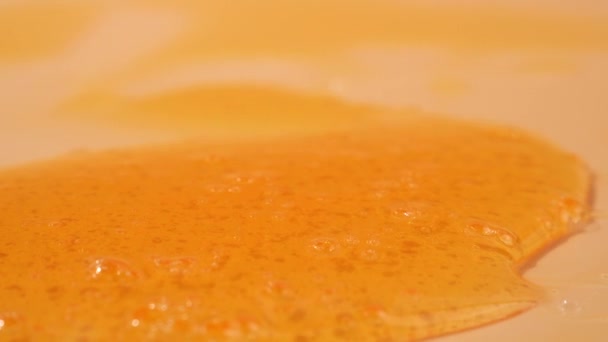 淋浴液凝胶优雅地流过明亮的橙色背景 淋浴液的半透明波产生了迷人的视觉交响乐 流经橙色背景的液体淋浴液 — 图库视频影像