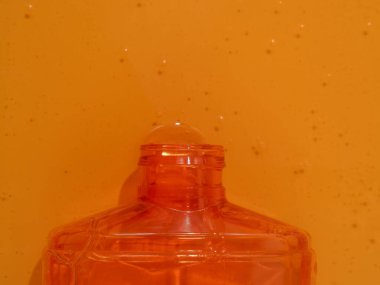 Sıvı duş jeli zarifçe parlak turuncu bir arka plan üzerine dökülür. Duş jeli kolayca akar, büyüleyici bir renk ve doku görüntüsü yaratır..