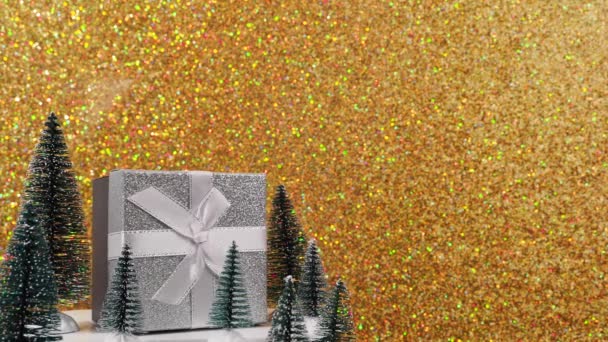 美しく包まれたギフトボックスは 輝く金色の背景に対して回転します お祝いの弓とリボンで飾られたギフトボックス 金色の背景にクリスマスプレゼント — ストック動画
