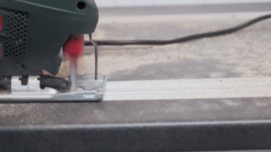 Bir adam mutfak lavabosu için bir yapbozla tezgahı keser, bir mutfak işçisi de elektrikli testereyle tezgahı keser. Mobilya kurulumu.