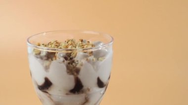 Parlak turuncu arka planda dönen dondurma. Plastik bardaktaki dondurma turuncu arka planda döner..