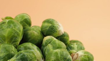 Brüksel lahanası turuncu arka planda döner. Turuncu arka planda taze, küçük Brüksel lahanaları.