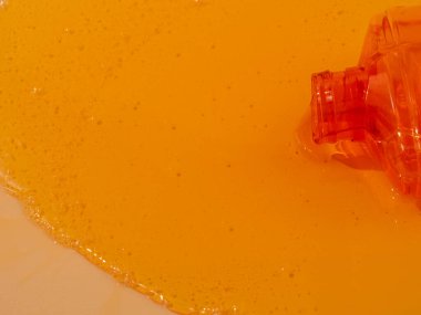 Sıvı duş jeli zarifçe parlak turuncu bir arka plan üzerine dökülür. Duş jeli kolayca akar, büyüleyici bir renk ve doku görüntüsü yaratır..