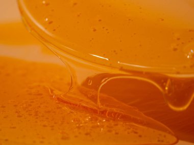 Sıvı duş jeli parlak turuncu bir arka planda zarifçe akar. Duş jelinin şeffaf dalgaları büyüleyici bir görsel senfoni yaratıyor. Sıvı duş jeli turuncu bir arka planda akar.