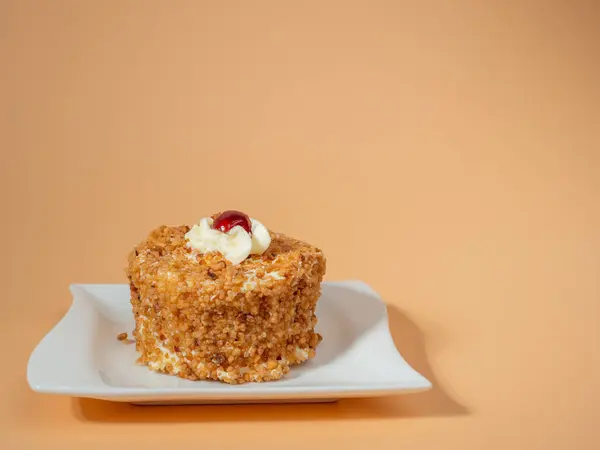 Butter cake with cherry filling on a bright orange background. Butter cake decorated with juicy cherries. A delicious butter cake topped with a single cherry on an orange surface.