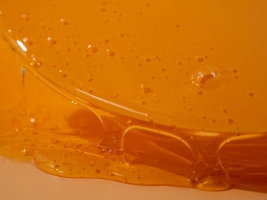 Sıvı duş jeli parlak turuncu bir arka planda zarifçe akar. Duş jelinin şeffaf dalgaları büyüleyici bir görsel senfoni yaratıyor. Sıvı duş jeli turuncu bir arka planda akar.
