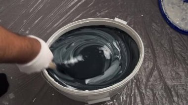 Bir işçi duvarları boyamak için bir kovaya boya karıştırır. Duvarları boyamaya hazırlanıyorum..
