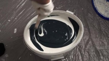 Bir işçi duvarları boyamak için bir kovaya boya karıştırır. Duvarları boyamaya hazırlanıyorum..