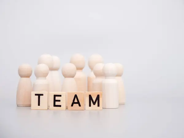 Wooden figures. The word TEAM and wooden figures on a gray background. Teamwork concept.