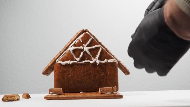 家の形をしたクリスマスジンジャーブレッド 砂糖のアイシングとクリスマスの前にジンジャーブレッドハウスを組み立てる — ストック動画