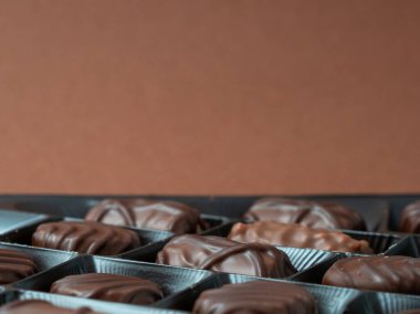 Zengin bir kahverengi arka planda çeşitli çikolata çeşitleri sıralanmış. Çikolatalı şekerler yakın plan..