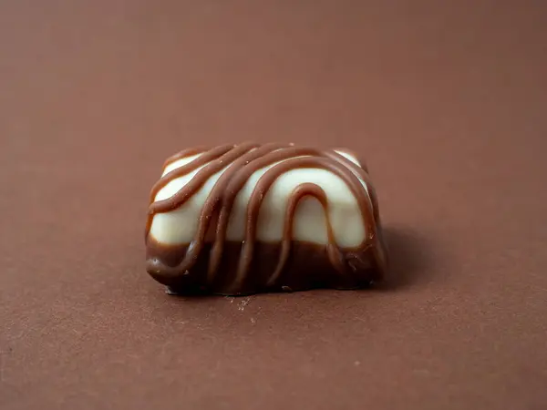 Chocolate candy arranged on a warm brown background. Chocolate candies close-up.