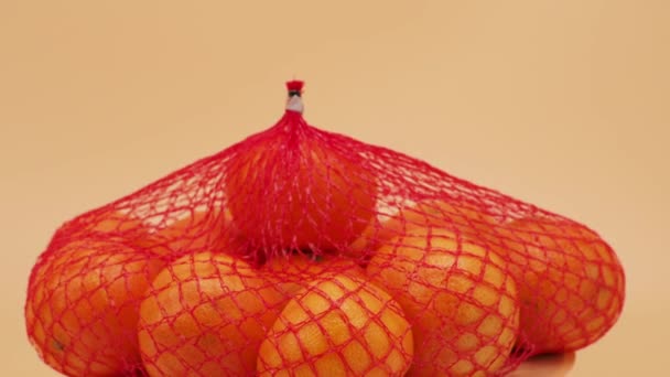 Grupa Tropikalnych Owoców Mandarynki Opakowaniu Siatkowym Obraca Się Pomarańczowym Tle — Wideo stockowe
