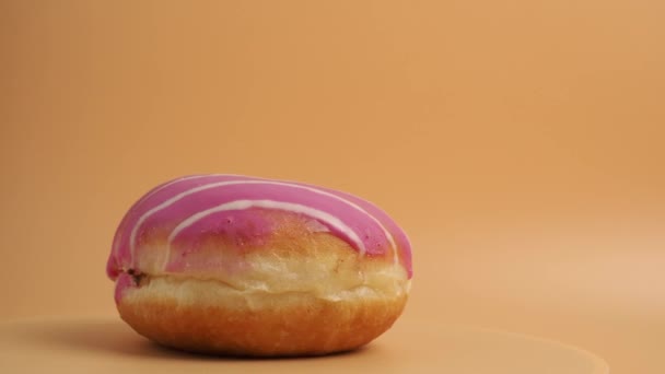 Donut Cubierto Con Glaseado Azúcar Roja Gira Sobre Fondo Naranja — Vídeos de Stock