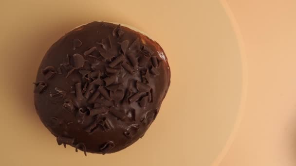 一个涂有巧克力片的甜甜圈在橙色背景下旋转 甜面包特写 — 图库视频影像