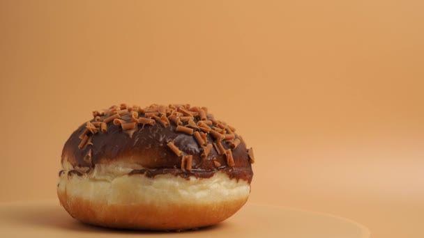 초콜릿 칩으로 초콜릿으로 도넛은 오렌지색 배경에서 회전합니다 달콤한 클로즈업 — 비디오