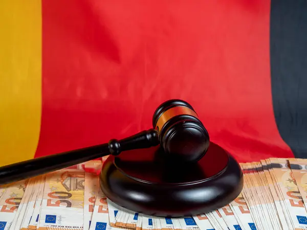 Hakimin tokmağı, Alman bayrağının arka planına karşı 50 avroluk banknotların üzerinde yer alıyor. Hukuk ve adalet kavramı.