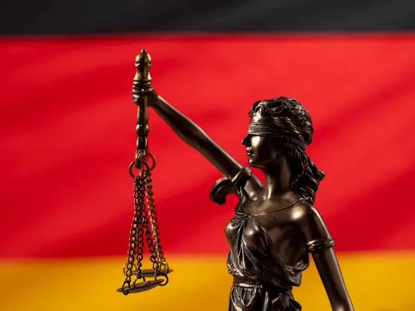 铜像的正义与德国国旗为背景 德国法律概念 免版税图库图片