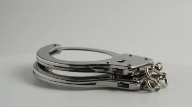 Polis kelepçeleri beyaz arka planda döner. Kelepçeler yakın plan..