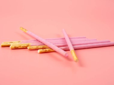 Pembe şeker kaplı çıtır çubuklar. Pembe arka planda böğürtlen pembesi jöleli çubuklar.