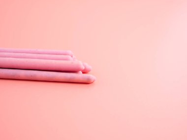 Pembe şeker kaplı çıtır çubuklar. Pembe arka planda böğürtlen pembesi jöleli çubuklar.