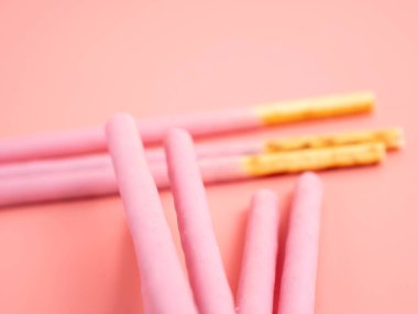 Pembe şeker kaplı çıtır çubuklar. Pembe arka planda böğürtlen pembesi jöleli çubuklar.