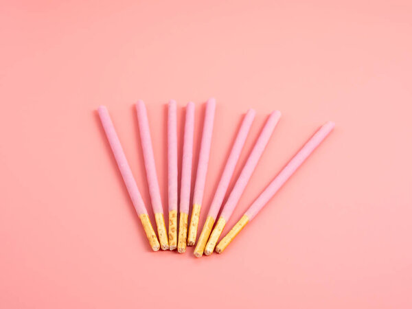 Хрустящие палочки в розовой глазури. Штрихи в розовом цвете на розовом фоне.