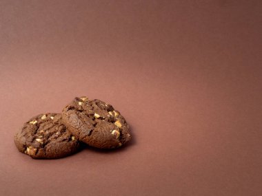 Çikolatalı, kahverengi arka planda beyaz çikolata parçacıkları olan zengin kurabiyeler. Beyaz çikolatalı kurabiyeler..