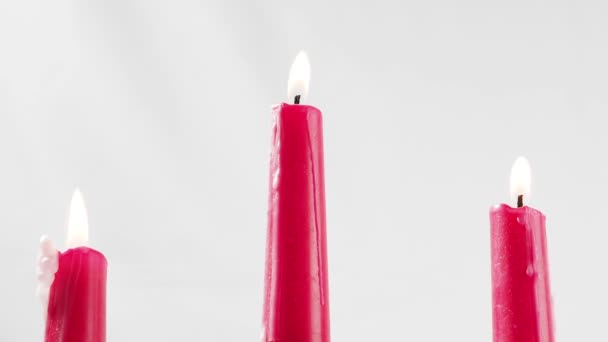 白色背景上有三支炽热的蜡烛红色蜡烛关上了 — 图库视频影像