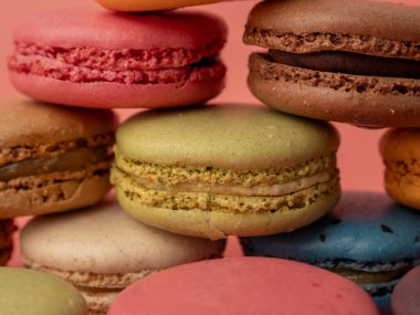 Pembe arka planda renkli Fransız kurabiyeleri. Fransız kurabiyeleri yakın plan..