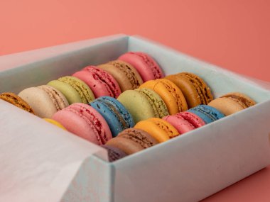 Pembe arka planda renkli Fransız kurabiyeleri paketliyorum. Fransız kurabiyeleri yakın plan..