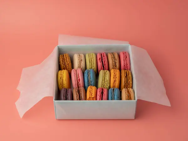 Packaging Colorful French macaroons on a pink background. French macaroons close-up.