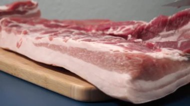 Siyah eldivenli bir adam kesme tahtasıyla domuz eti kesiyor. Domuz eti kesme konusunda yüksek lisans..