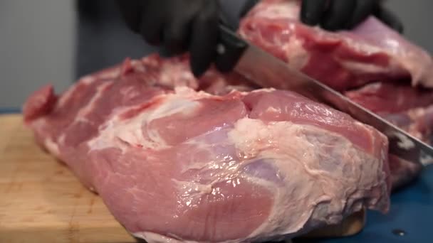 黒い手袋の男は 切断板に豚肉を切断する 豚肉切断スキルを実証した経験豊富な肉屋 — ストック動画