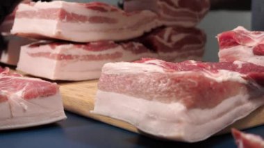 Siyah eldivenli bir adam kesme tahtasıyla domuz eti kesiyor. Yakın plan et bir profesyonel tarafından doğranıyor..