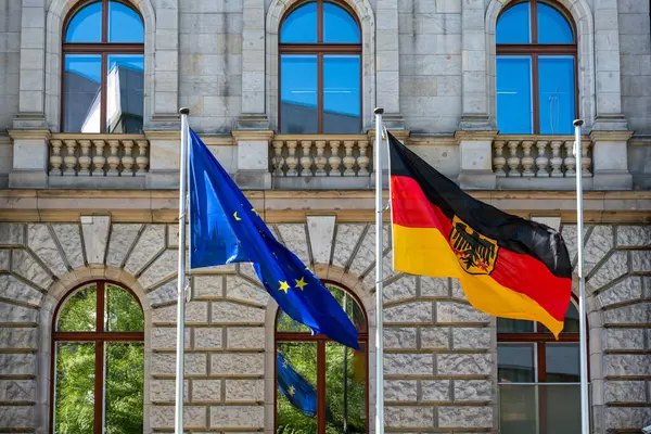 Waving German and European Union flag against the background of a historical building. German flag and European Union close-up.