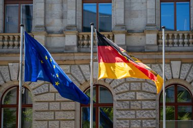 Tarihi bir binanın arka planında Alman ve Avrupa Birliği bayrağı sallıyordu. Alman bayrağı ve Avrupa Birliği yakın çekim.