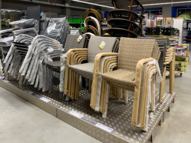 Almanya 11 Mayıs 2024. Bir mağazanın rafında sandalye ve masalar da dahil olmak üzere açık hava mobilyaları sergileniyor. Sandalyeler hasırdan yapılmış ve sırayla dizilmiş.