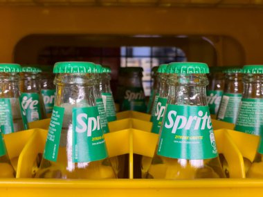 Germany Berlin May 11, 2024. A row of green bottles of Sprite are lined up in a yellow container. The bottles are all the same size and shape, and they all have the same label. Concept of uniformity and organization clipart