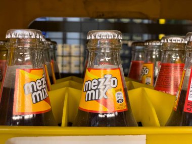 Almanya 11 Mayıs 2024. Bir sıra Mezzo Mix şişesi rafa dizildi. Şişelerin hepsi aynı boyut ve şekildeydi ve hepsi de temizdi.